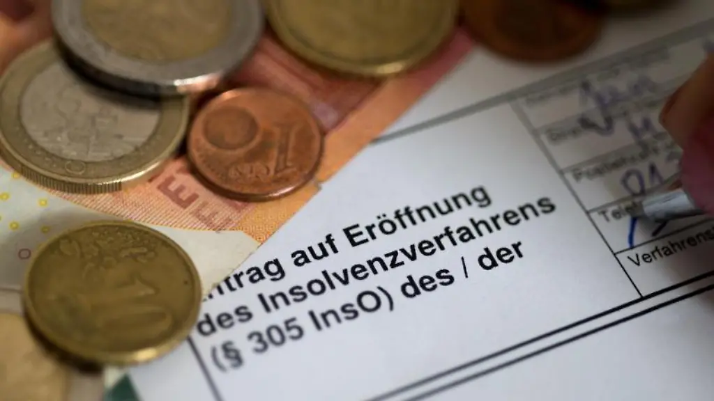 Ein-Antrag-auf-Eroeffnung-des-Insolvenzverfahrens-liegt-neben-Muenzen-und-einem-10-Euro-Schein-auf-dem-Tisch