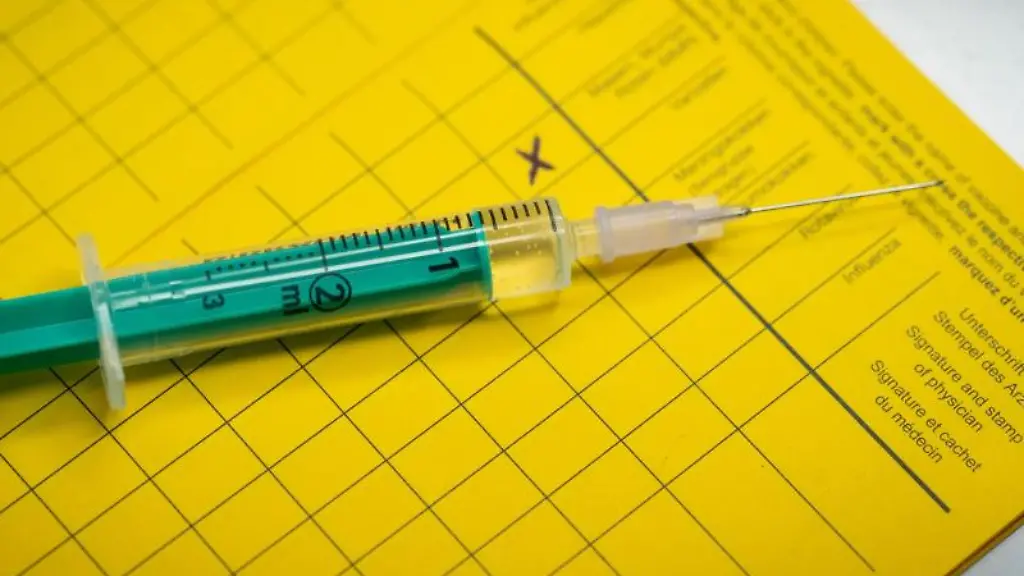 Eine-Spritze-liegt-auf-einem-Impfpass