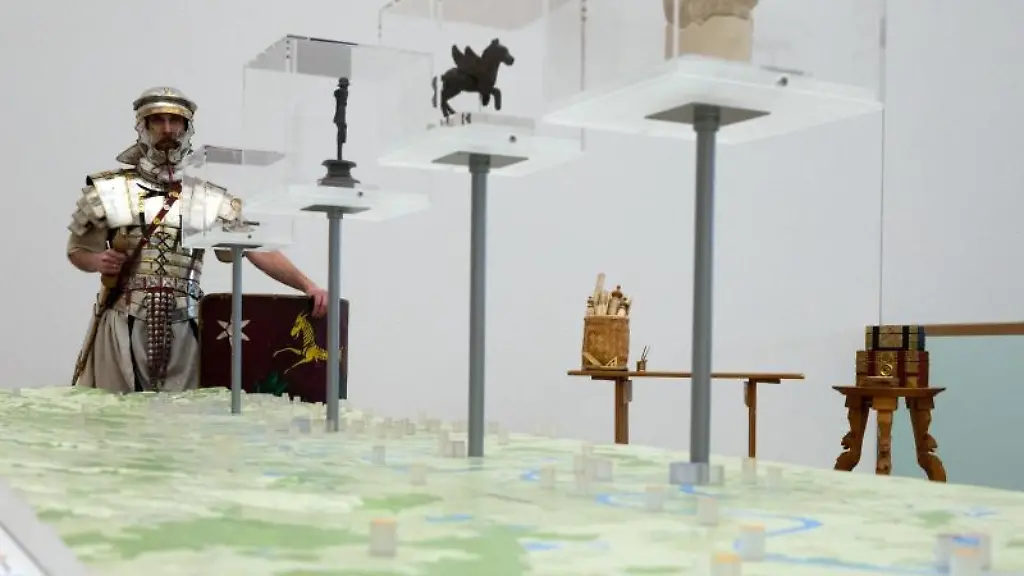 Ein-Mann-steht-in-der-Ruestung-eines-Legionaers-vor-einem-Modell-des-niedergermanischen-Limes