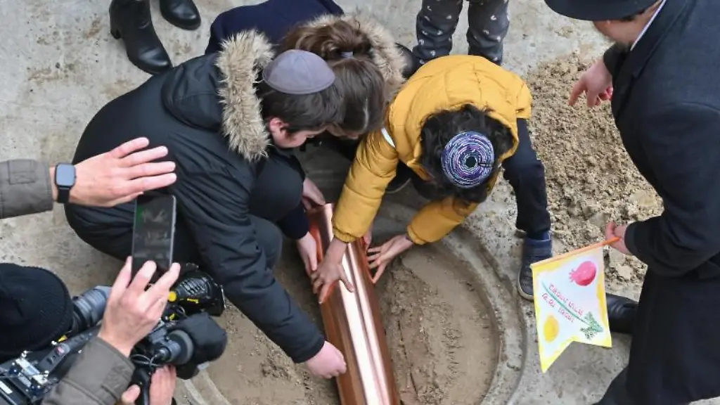 Kinder-legen-eine-kupferne-Dokumentenrolle-zur-Grundsteinlegung-fuer-die-Synagoge-Potsdam-in-die-Erde