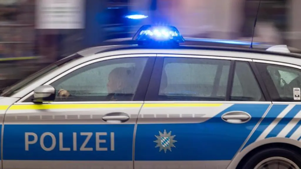 Ein-Fahrzeug-der-bayerischen-Polizei-faehrt-mit-Blaulicht-durch-die-Innenstadt