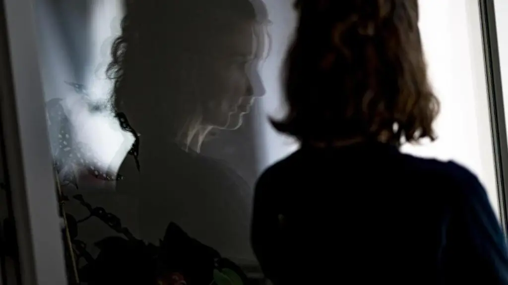 Eine-junge-Frau-steht-in-einem-geoeffneten-Fenster