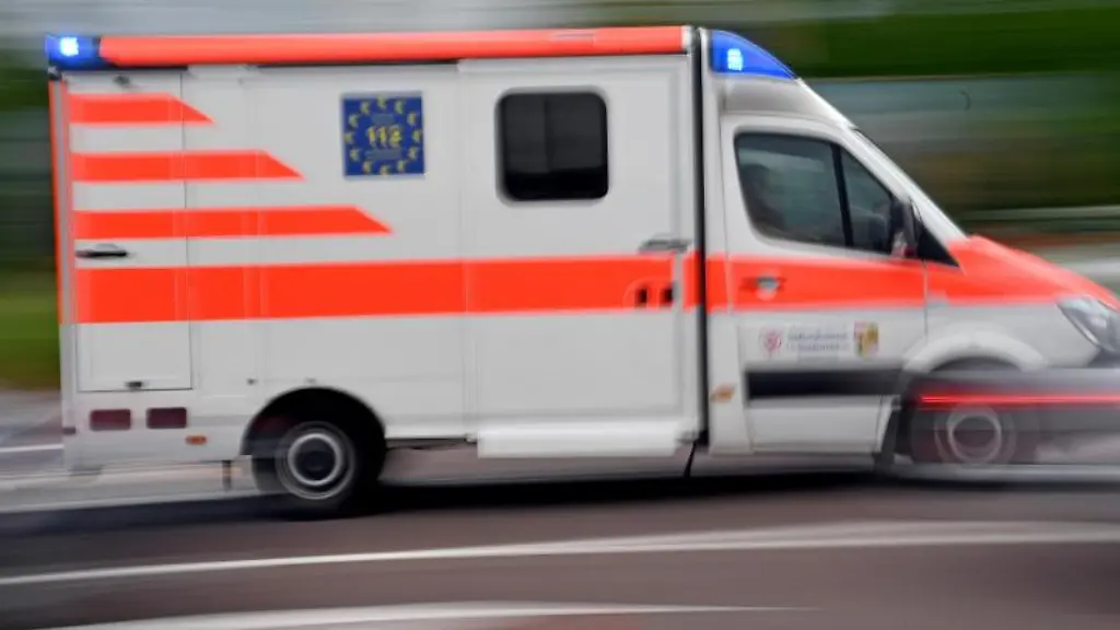 Ein-Krankenwagen-faehrt-mit-Blaulicht-auf-einer-Strasse