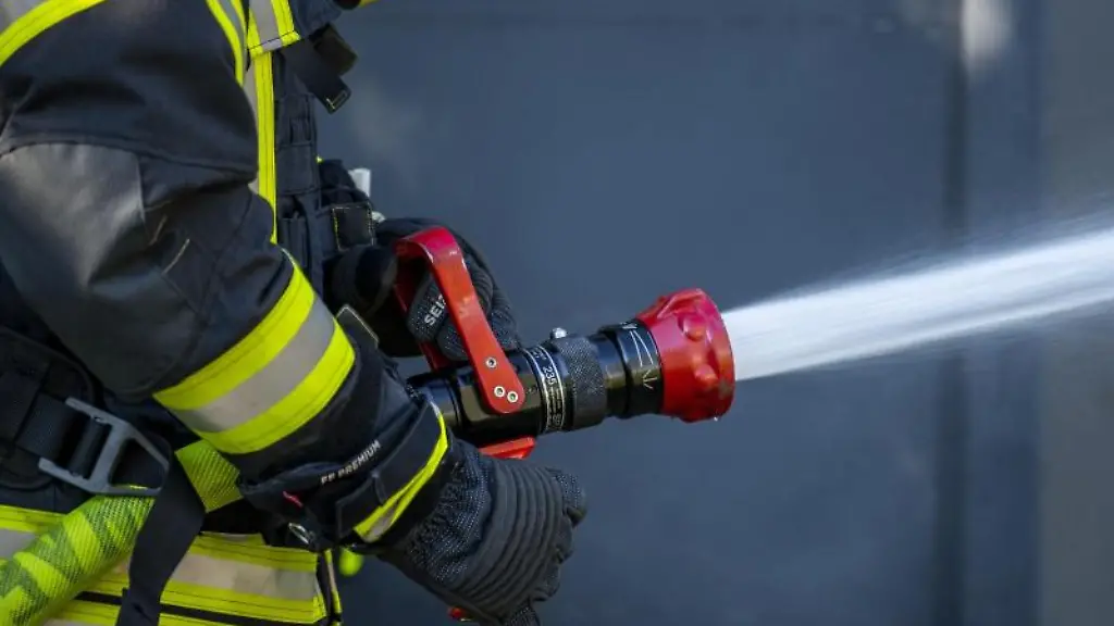 Ein-Mitglied-der-Feuerwehr-spritzt-aus-einem-Schlauch-mit-Wasser
