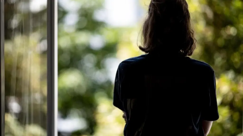 Eine-junge-Frau-steht-vor-einem-geoeffneten-Fenster