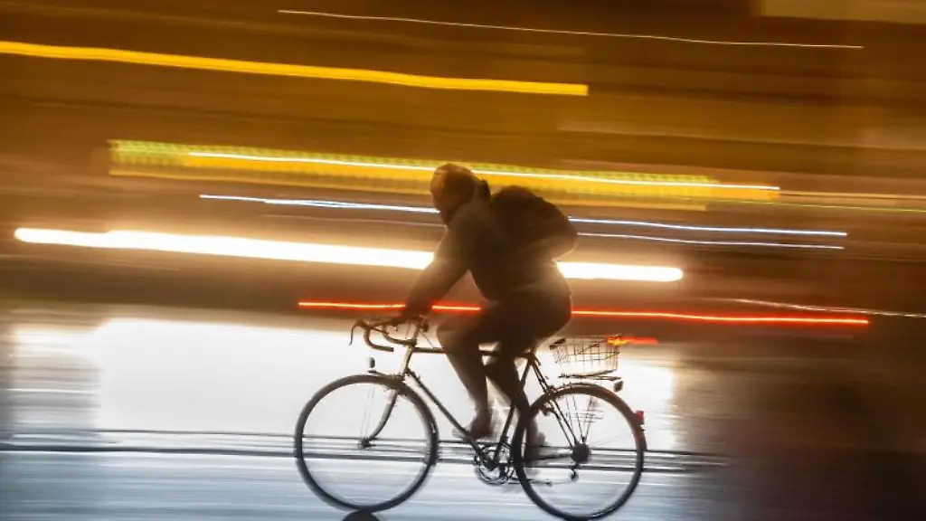 Ein-Radler-faehrt-am-Abend-auf-einer-Strasse-in-der-Innenstadt