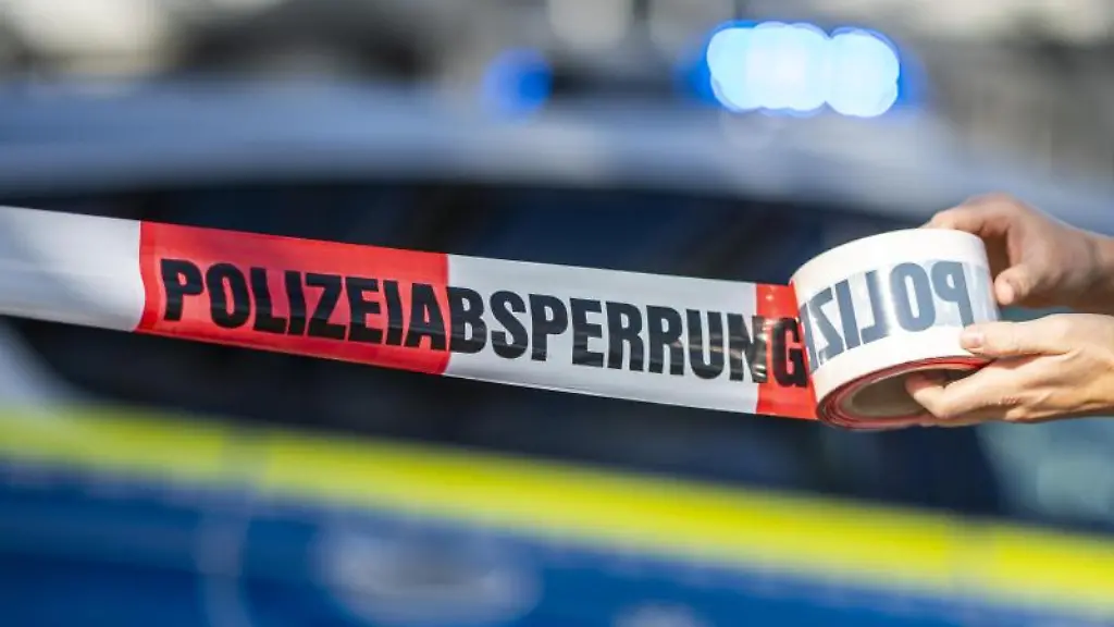Eine-Frau-rollt-ein-Absperrband-der-Polizei-aus