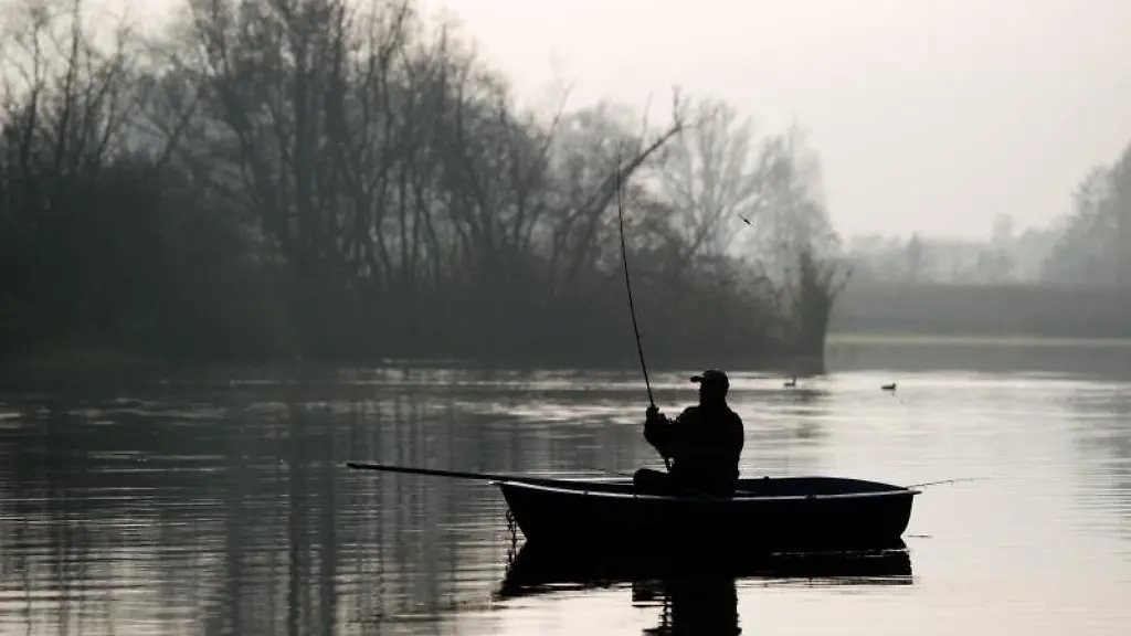 Ein-Angler-sitzt-in-seinem-Boot-auf-der-Spree-und-wirft-seine-Angel-aus