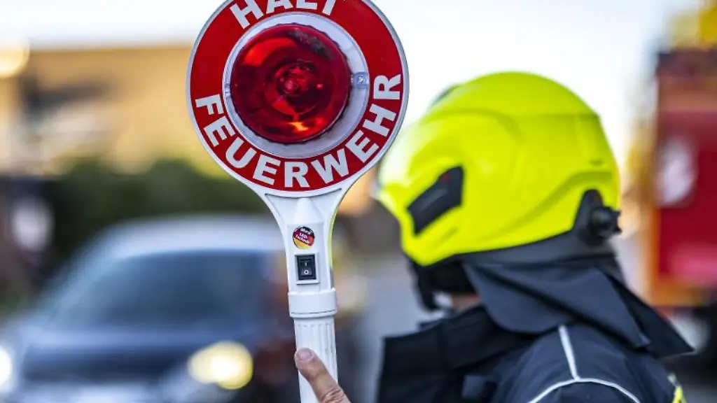 Ein-Mitglied-der-Feuerwehr-haelt-eine-Kelle-mit-der-Aufschrift-Halt-Feuerwehr-in-die-Hoehe