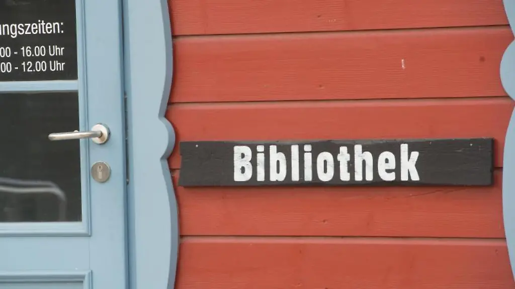 Eins-Schild-mit-dem-Schriftzug-Bibliothek-haengt-in-Prerow-neben-einer-Tuer