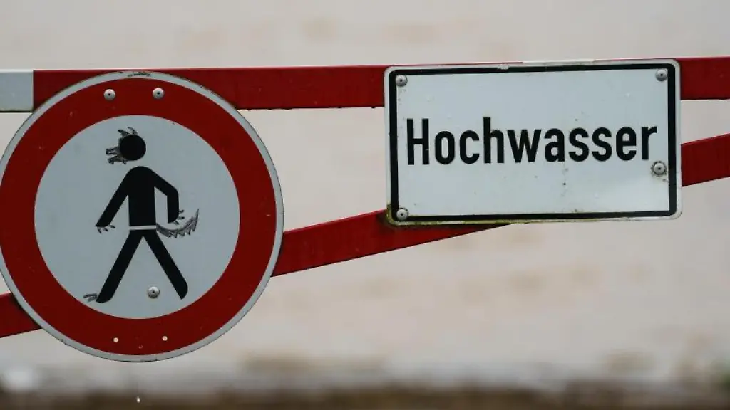 Ein-Hochwasser-Schild-steht-an-einem-ueberfluteten-Feld