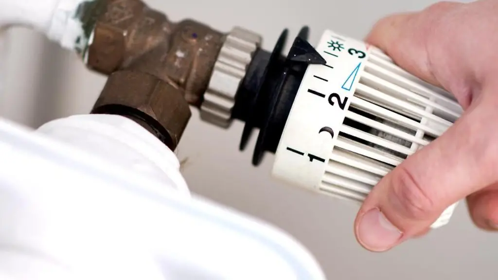 Eine-Frau-dreht-am-Thermostat-einer-Heizung