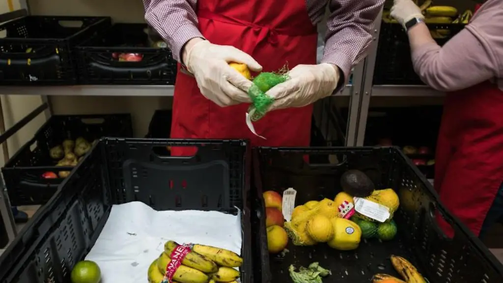 Zwei-ehrenamtliche-Helfer-sortieren-gespendetes-Obst-aus