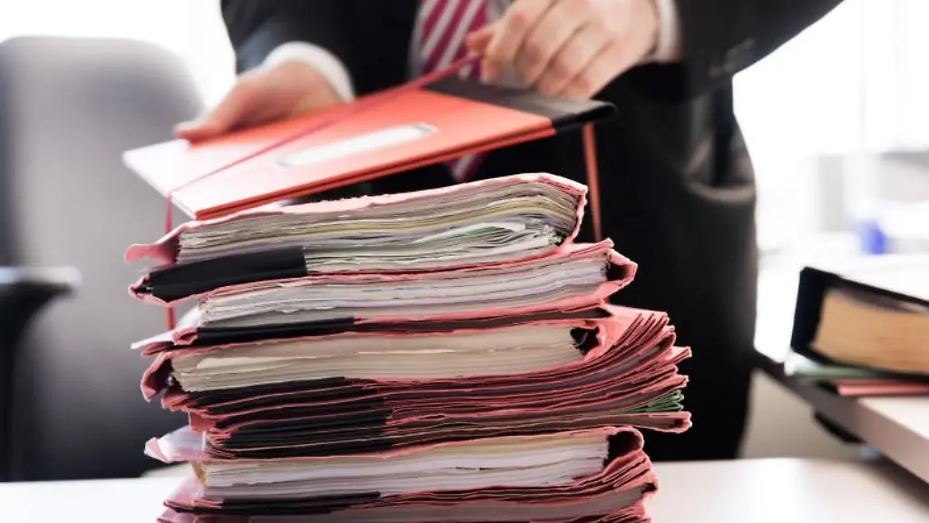 Ein-Staatsanwalt-steht-vor-einem-Stapel-Gerichtsakten