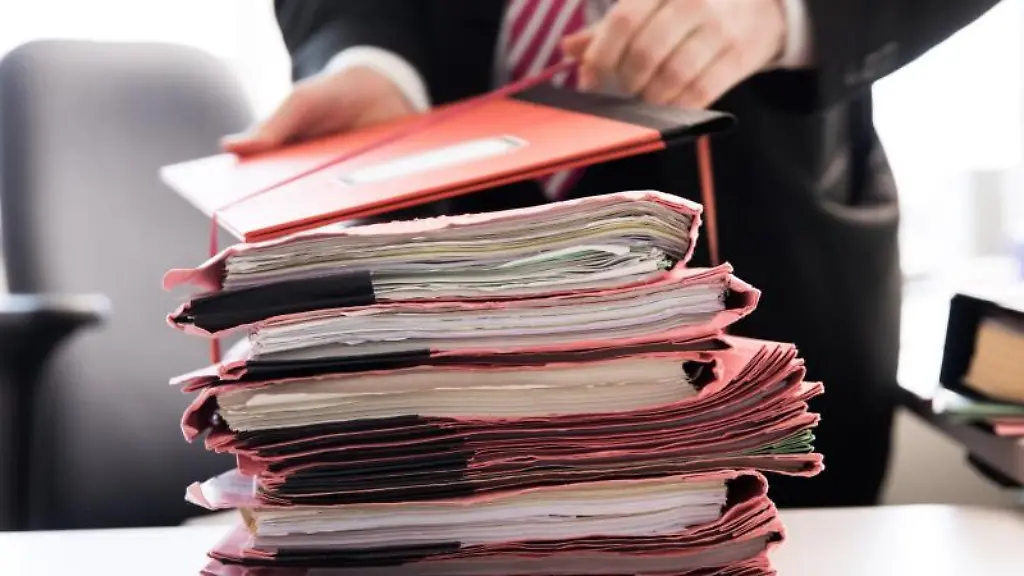 Ein-Staatsanwalt-steht-vor-einem-Stapel-Gerichtsakten