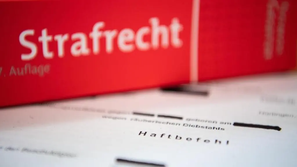 Eine-Abschrift-eines-Haftbefehls-liegt-mit-einem-Strafrecht-Buch-auf-dem-Tisch