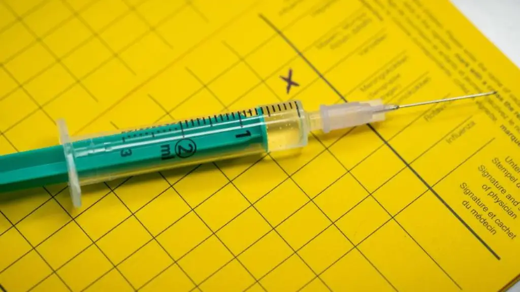 Eine-Spritze-liegt-auf-einem-Impfpass
