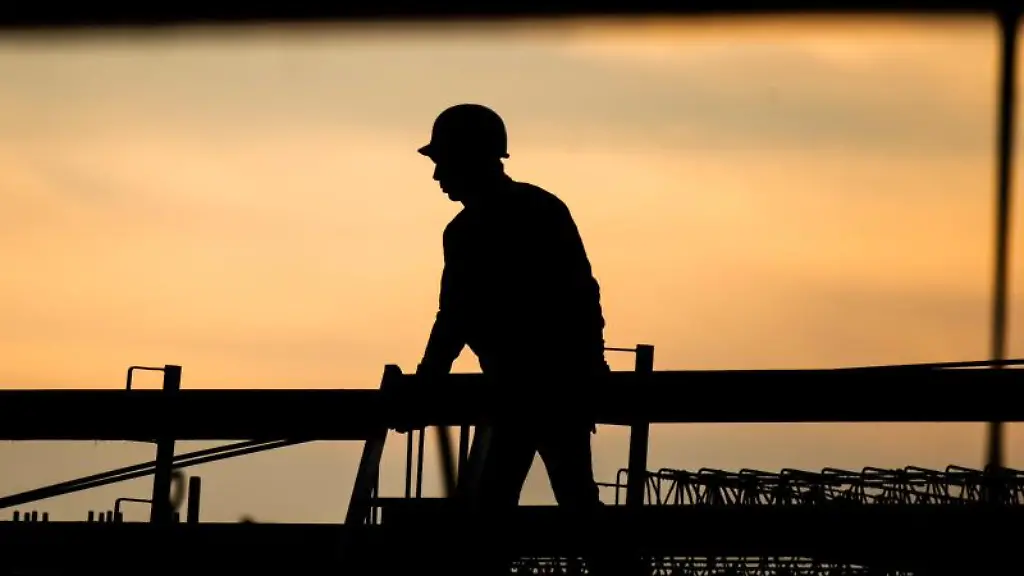 Die-Silhouette-eines-Bauarbeiters-zeichnet-sich-auf-einer-Baustelle-vor-dem-Morgenhimmel-ab