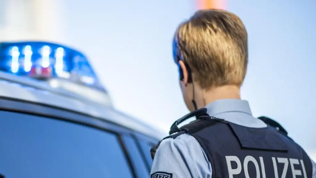 Eine-Polizistin-steht-vor-einem-Streifenwagen