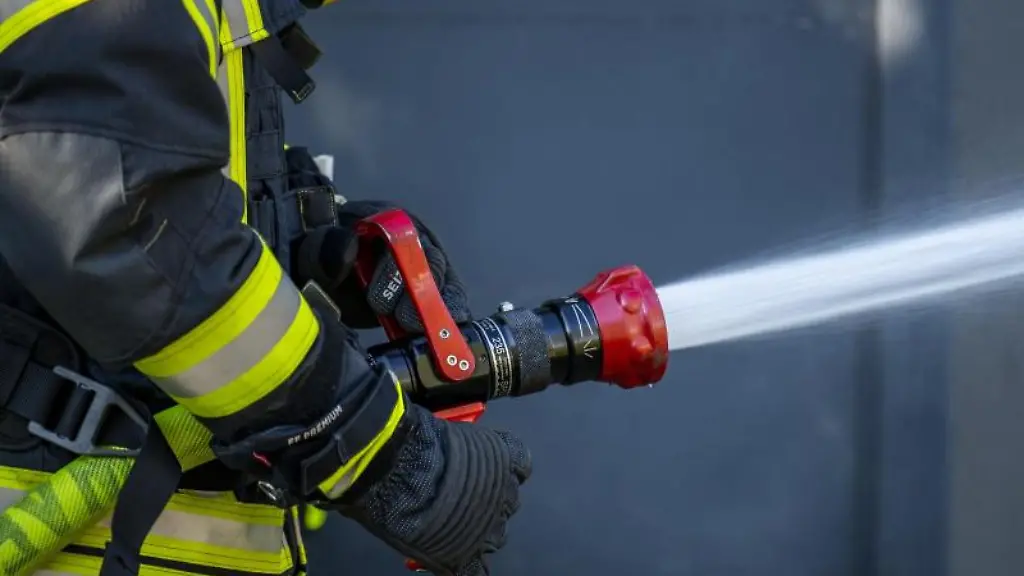 Ein-Mitglied-der-Feuerwehr-spritzt-aus-einem-Schlauch-mit-Wasser