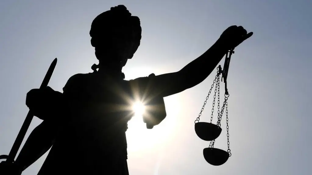 Eine-Statue-der-Justitia-steht-mit-Waage-und-Schwert-in-der-Hand