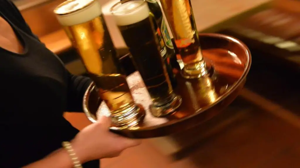 Eine-Bedienung-traegt-ein-Tablett-mit-Bier-in-einem-Lokal
