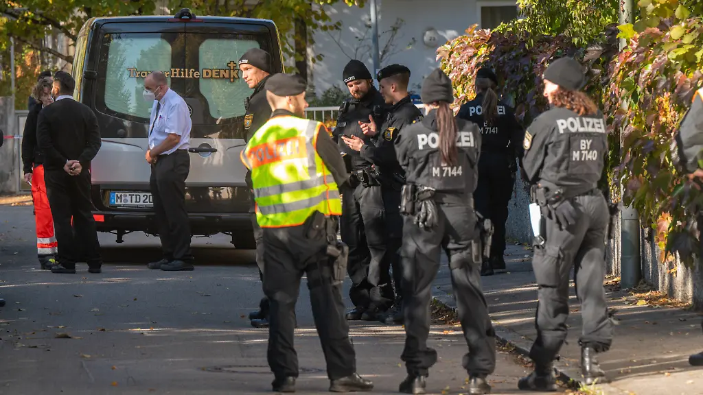 Ein-Bestatter-Mitarbeiter-des-Deutschen-Roten-Kreuzes-und-Polizisten-stehen-vor-dem-Tatort-im-Muenchner-Stadtbezirk-Bogenhausen