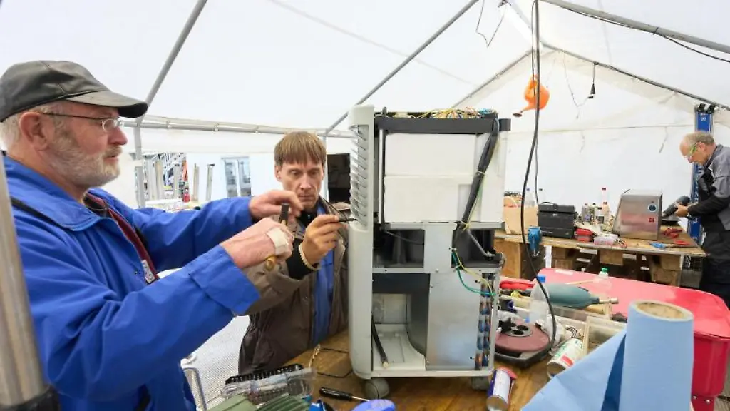 Die-beiden-Elektroseelsorger-Thomas-l-und-Iwer-reparieren-im-Werkstattzelt-einen-Bautrockner