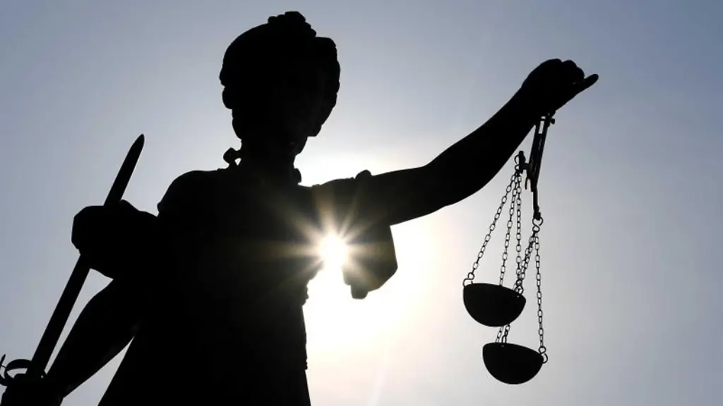 Eine-Statue-der-Justitia-steht-mit-Waage-und-Schwert-in-der-Hand