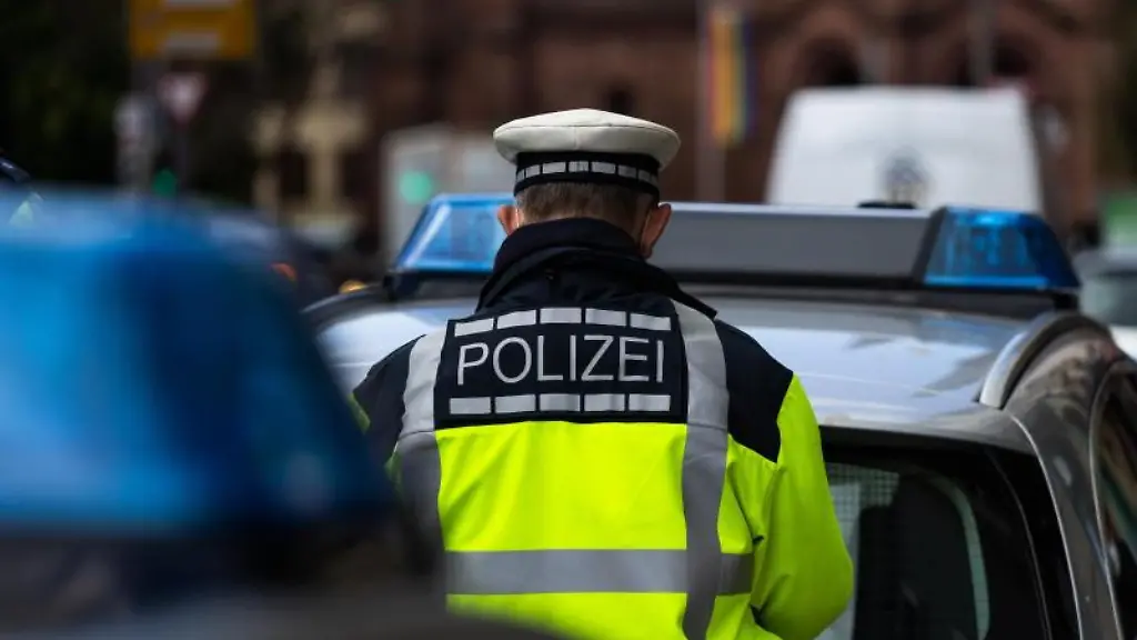 Ein-Polizeibeamter-steht-zwischen-zwei-Einsatzfahrzeugen