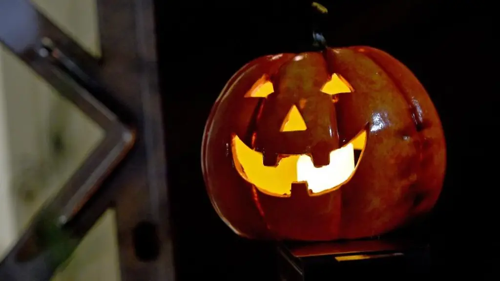 Ein-Dekokuerbis-mit-Gesicht-leuchtet-vor-einer-geschlossenen-Haustuer