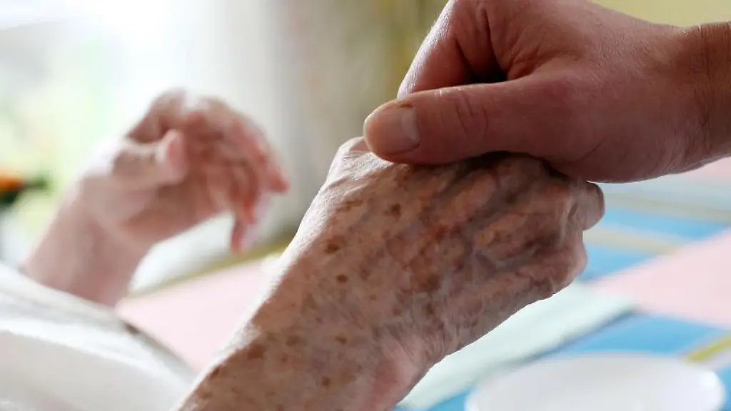 Ein-Pfleger-haelt-in-einem-Alten-und-Pflegeheim-die-Hand-einer-Bewohnerin