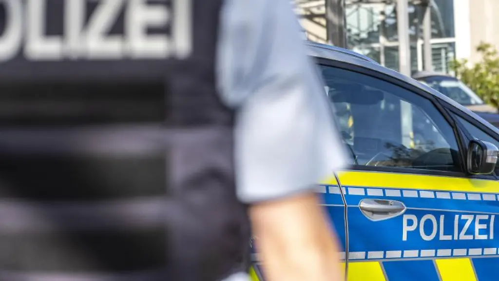 Ein-Polizist-steht-vor-einem-Streifenwagen