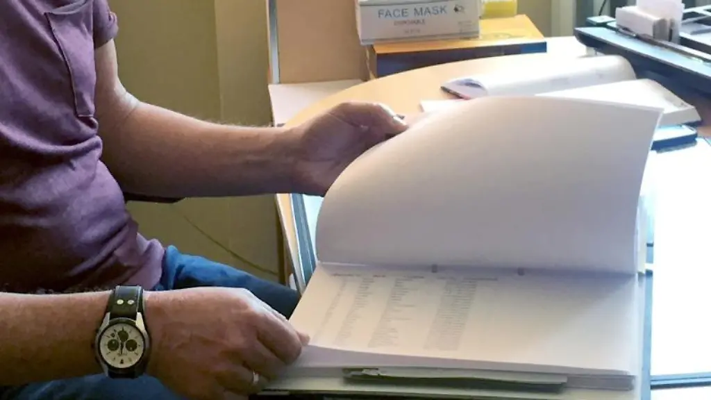 Der-Mitarbeiter-eines-Gesundheitsamts-sitzt-an-seinem-Schreibtisch-und-blaettert-in-Akten