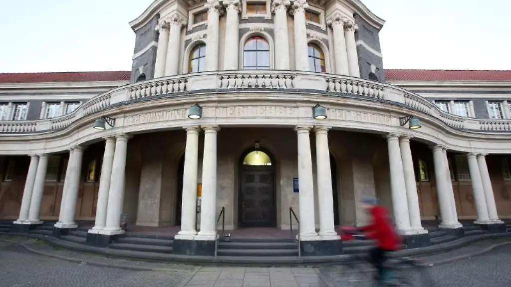 Eine-Frau-faehrt-mit-einem-Fahrrad-an-dem-Hauptgebaeude-der-Universitaet-Hamburg-vorbei