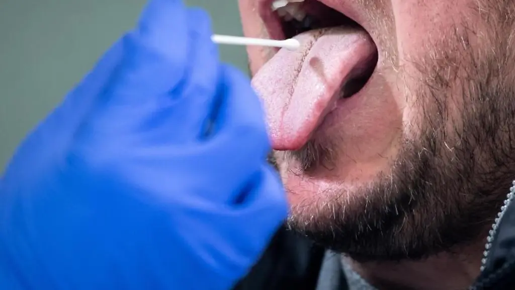 Ein-Medizinischer-Mitarbeiter-fuehrt-in-einem-Covid-19-Testcenter-einen-Rachenabstrich-bei-einem-Mann-durch