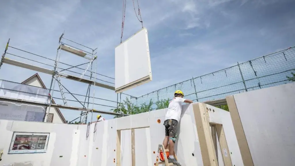 Ein-Bauarbeiter-steht-auf-einer-Leiter-und-arbeitet-im-Rohbau-eines-Fertighauses