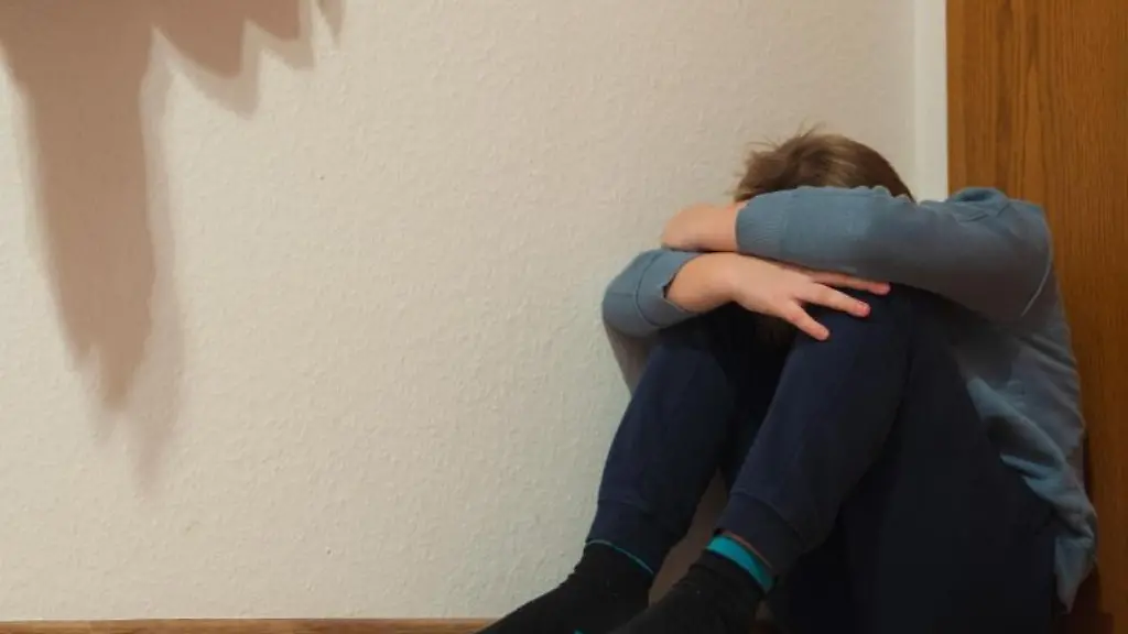 Ein-Junge-sitzt-in-der-Ecke-seines-Zimmers-am-Fussboden-und-kauert-sich-zusammen