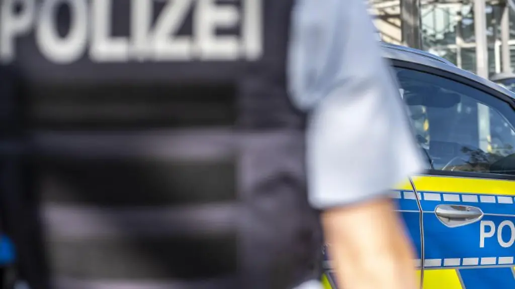 Ein-Polizist-steht-vor-einem-Streifenwagen