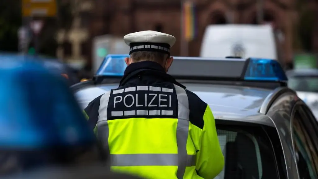 Ein-Polizeibeamter-steht-zwischen-zwei-Einsatzfahrzeugen