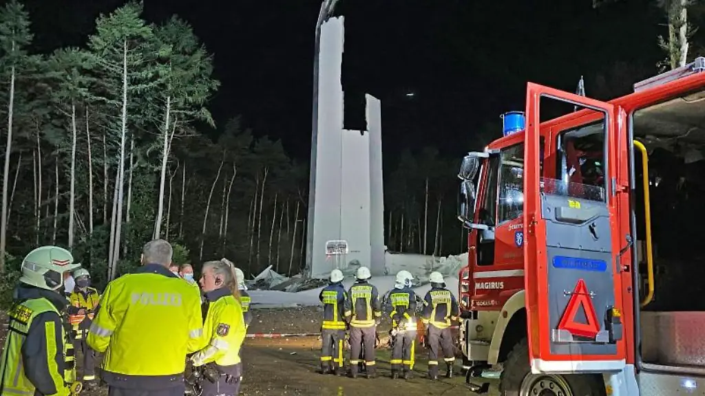 Feuerwehrleute-und-Polizisten-stehen-von-den-Resten-des-Turms-einer-Windenergieanlage-im-Wald