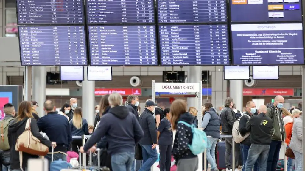 Reisende-sind-am-Flughafen-Hamburg-unterwegs-und-gehen-an-einer-Anzeigetafel-entlang