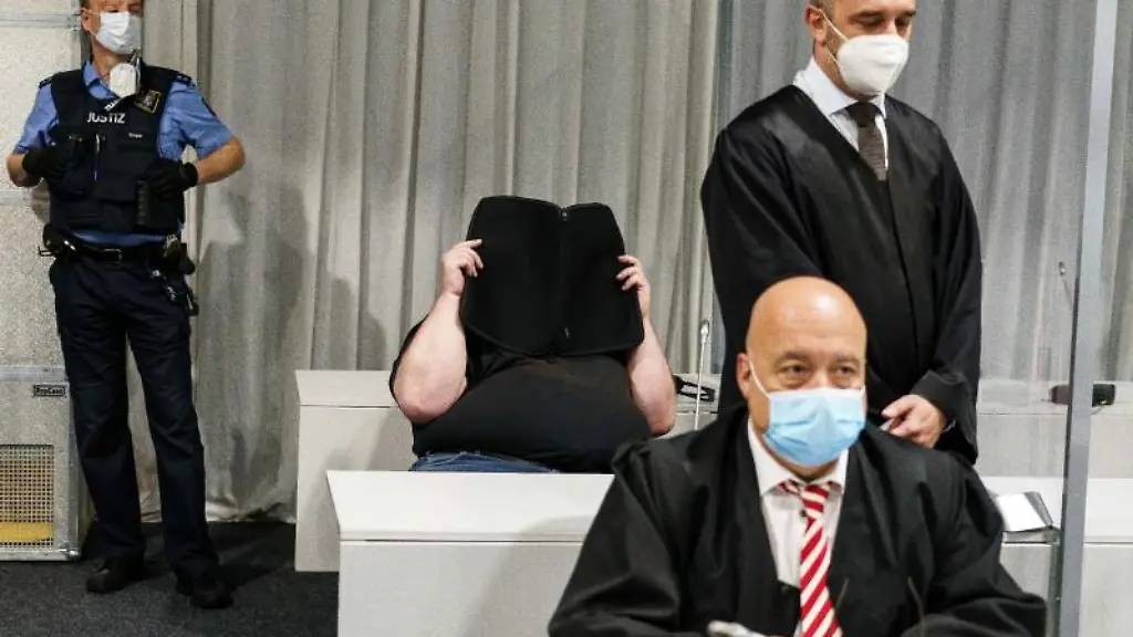 Ein-Justizmitarbeiter-der-Angeklagte-und-die-Anwaelte-des-Angeklagten-warten-auf-den-Prozessbeginn