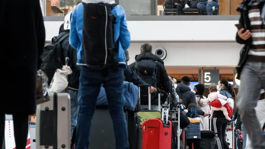 Flugreisende-gehen-durch-das-Abflugterminal-1-und-stehen-in-einer-langen-Schlange-an-einem-Check-In-Schalter