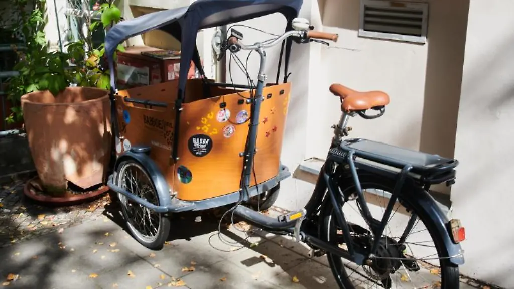 Ein-mit-Aufklebern-beklebtes-Lasten-Fahrrad-steht-vor-einem-Haus