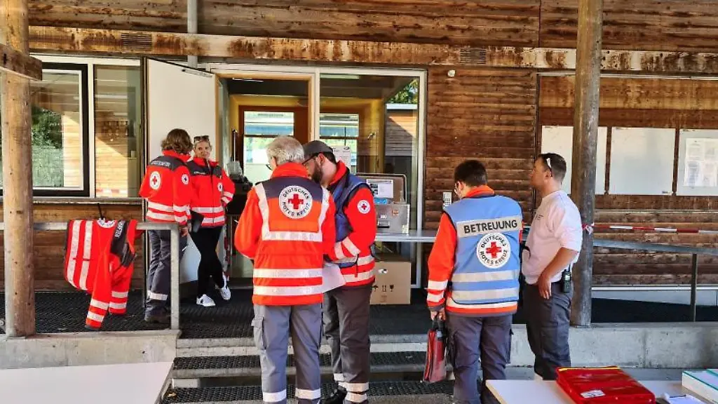 Mitarbeiter-des-Deutschen-Roten-Kreuzes-stehen-vor-einer-Berghuette