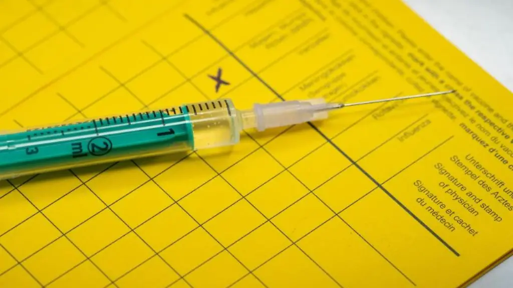 Eine-Spritze-liegt-auf-einem-Impfpass