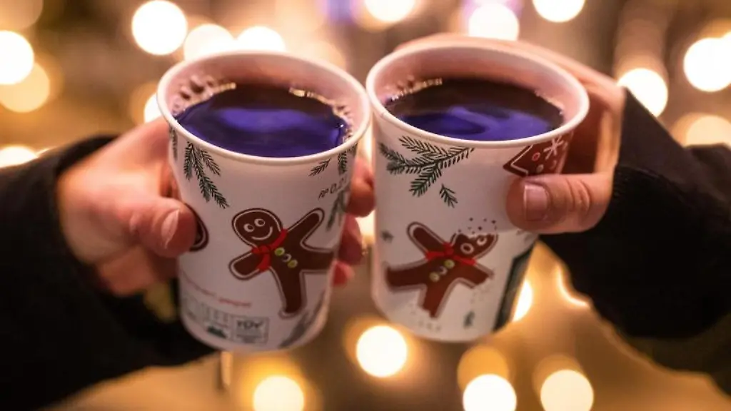 Zwei-Besucherinnen-eines-Weihnachtsmarktes-stossen-mit-Gluehwein-an