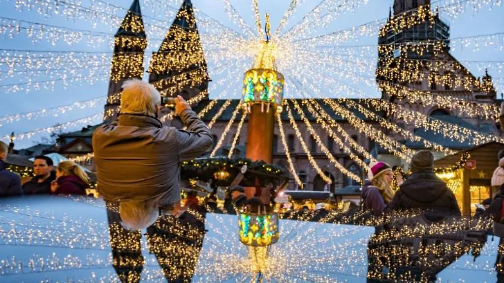 Ein-Besucher-des-festlich-beleuchteten-Weihnachtsmarktes-in-Mainz-macht-Fotos-vom-Dom