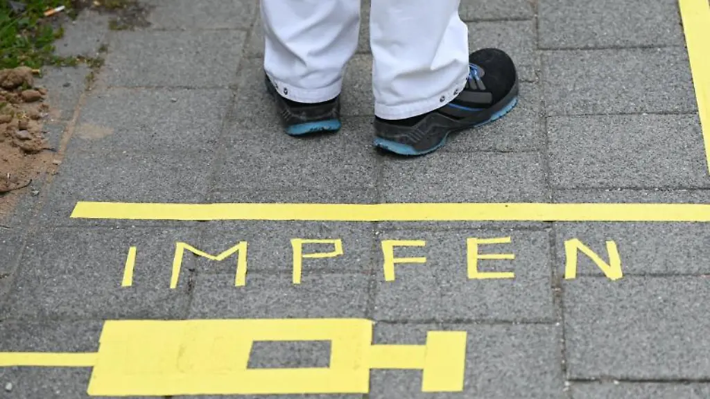 Ein-Mann-steht-an-einem-Covid-19-Impfcenter-hinter-der-Bodenaufschrift-Impfen